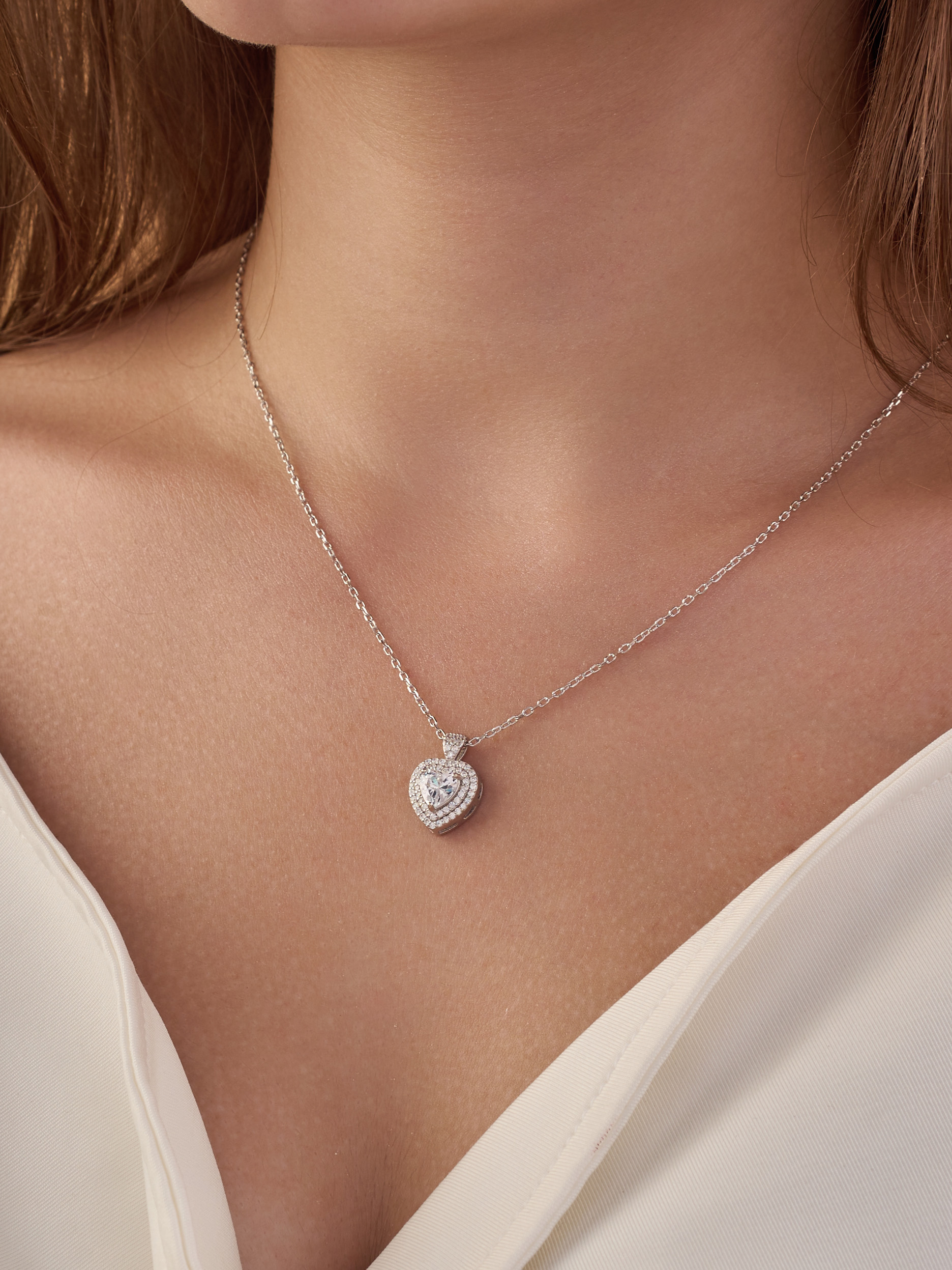Silver necklace in the shape of a heart , inlaid with white zircon stones.
