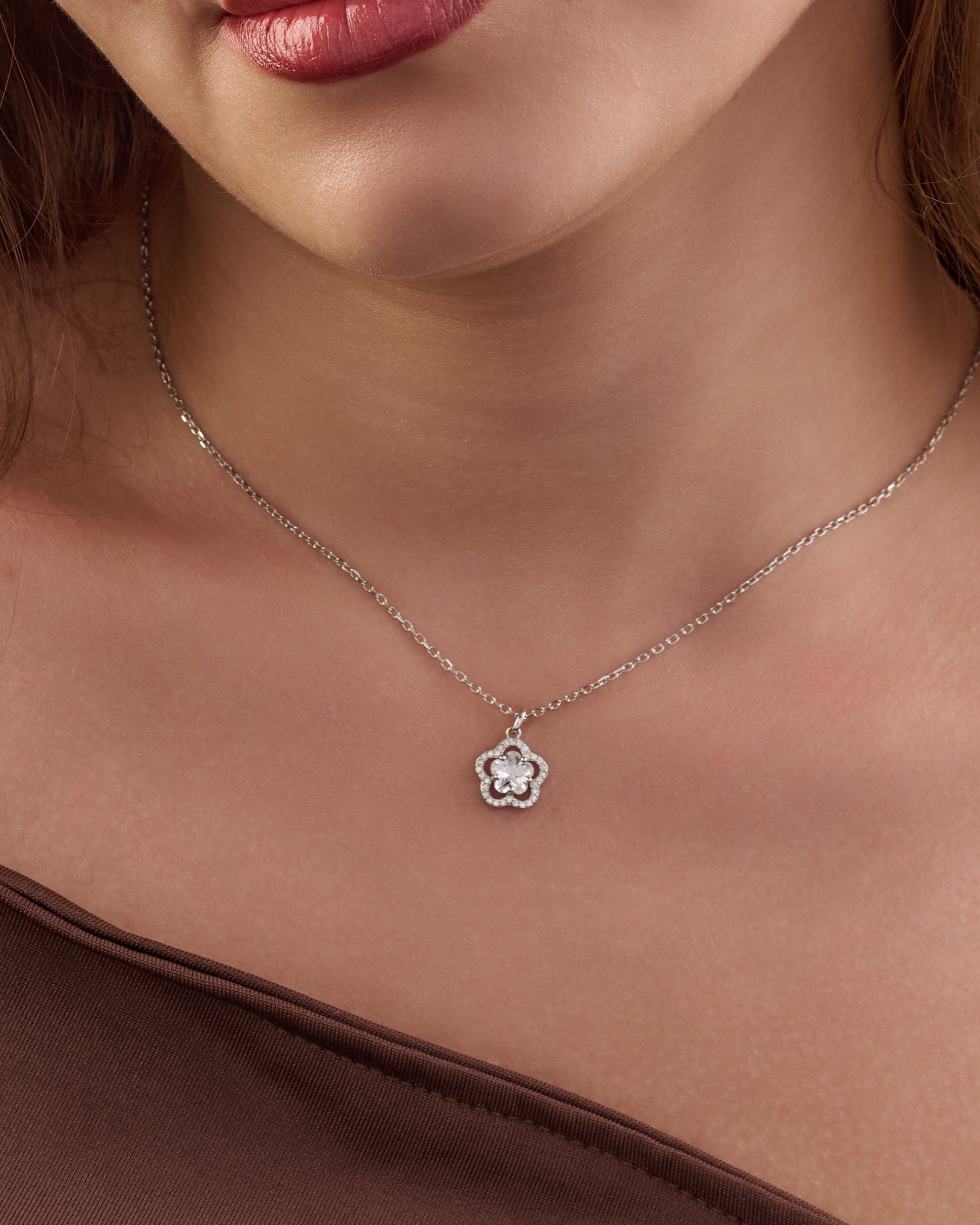 A simple silver necklace in the shape of a rose, featuring a white stone inlaid with white zircon stones.